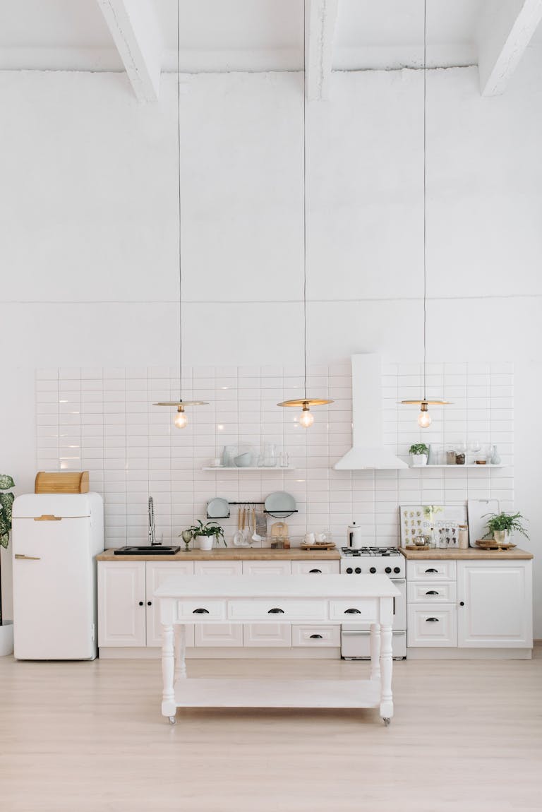 A minimalist white kitchen interior with modern appliances and decor elements.