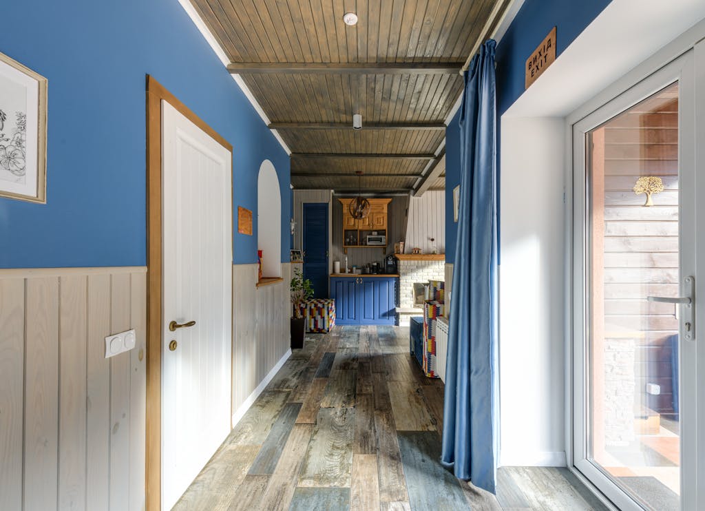 Modern residential hallway with blue decor and wood flooring.
