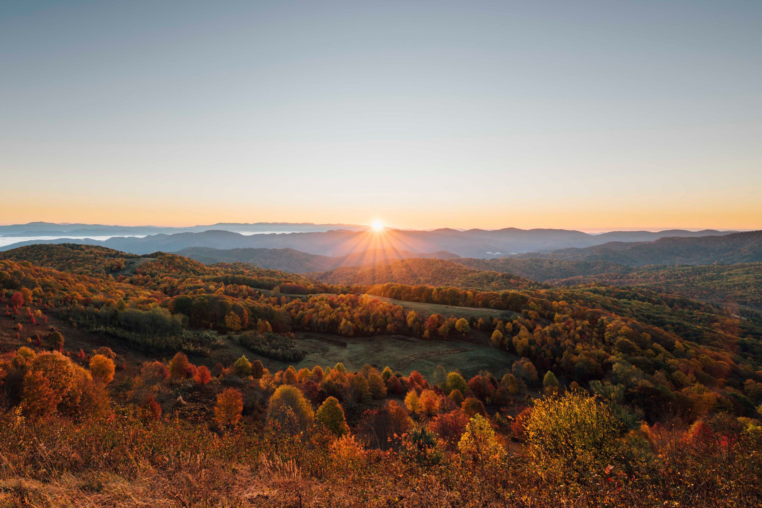 Breathtaking sunrise over autumn foliage in Hot Springs, NC mountains.